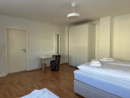 Heller, modern eingerichteter Raum mit zwei Betten, Tisch und Stuhl.