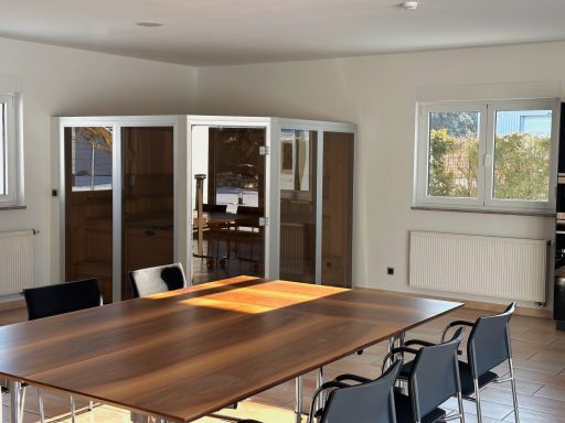 Ein heller Raum mit einem großen Tisch, Stühlen und Sauna.
