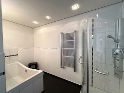 Helle Badezimmeransicht mit Dusche, Badewanne und Handtuchhalter.