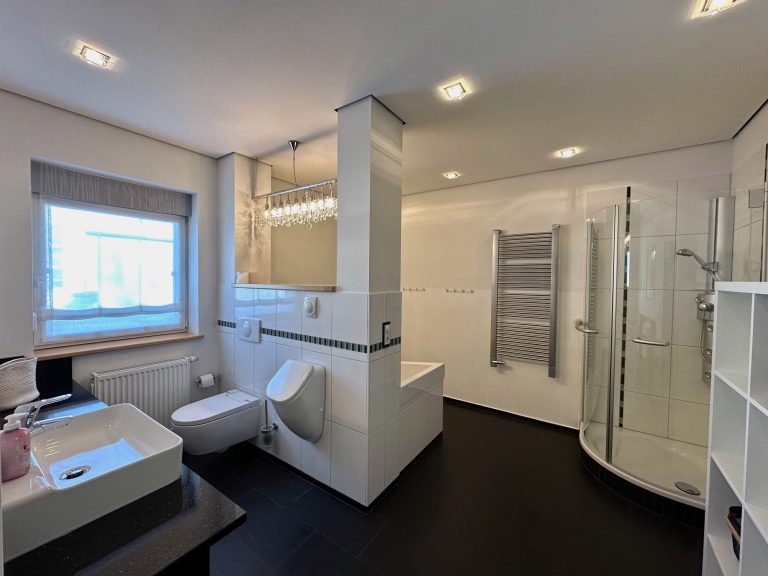 Heller, moderner Badezimmer mit Dusche, Waschbecken und minimalistischer Einrichtung.