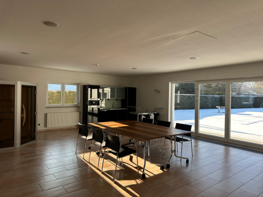 Heller, moderner Raum mit Esstisch, Stühlen, Bar, Sauna und großen Fensterflächen.