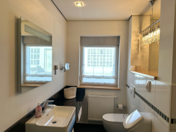 Heller, moderner Badezimmerraum mit Waschbecken, Toilette und zwei Spiegeln.