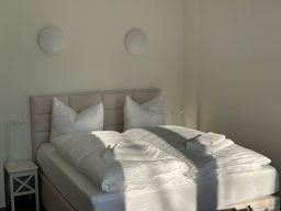 Kuscheliges Schlafzimmer mit Doppelbett, weißen Kissen und sanfter Beleuchtung.