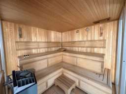 Holzsauna mit mehreren Bänken und einem Ofen in einer ruhigen Umgebung.