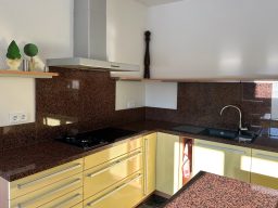 Moderne Küche mit gelben Schränken, braunem Marmorarbeitsplatz und Edelstahlarmatur.